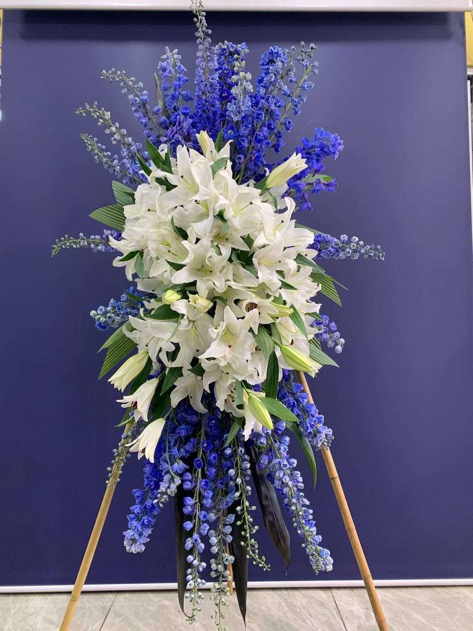 Blue Memories Standing Spray White lily standing spray for funeral & sympathy — Flower Empire Aurora florist serving North Yo
