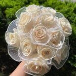 Cascading-style cream-rose bridal bouquet with organza, ribbon, and pearl detailing.