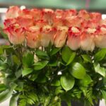 Two-tone red-and-cream High Magic roses with greenery in a luxury black box by Flower Empire.