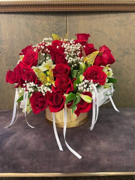 Large cascading red-rose arrangement in a gold vase with baby's breath, alstroemeria, and gold butterflies.