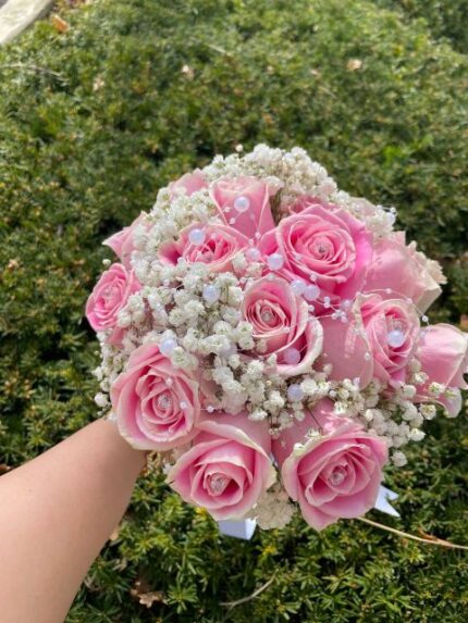 Romantic pink-rose bridal bouquet with baby's breath, pearl strands, and satin ribbon.