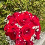 Lush red-rose bridal bouquet with baby's breath and pearl strand accents.