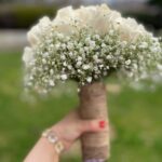 White roses and baby's breath bridal bouquet with rustic burlap-twine wrapped handle.