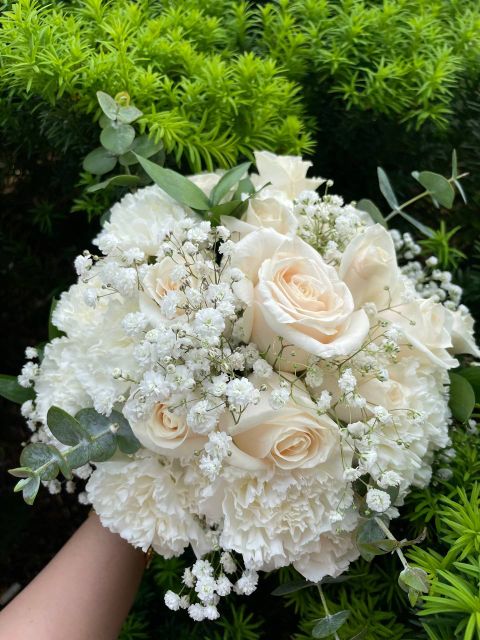 Mixed bridal bouquet of white roses, carnations, baby's breath, and eucalyptus greens.