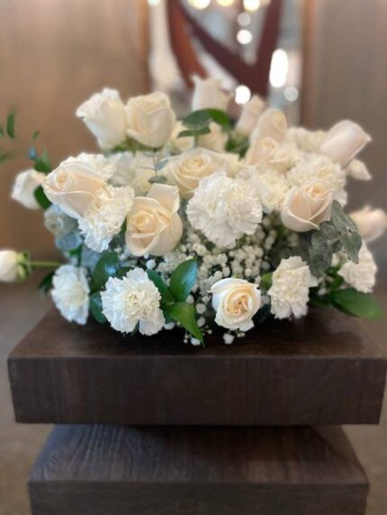 White roses, white carnations, baby's breath, and eucalyptus sympathy centerpiece by Flower Empire.