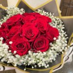 Red roses surrounded by a halo of white baby's breath in black-and-gold wrapping