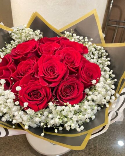 Red roses surrounded by a halo of white baby's breath in black-and-gold wrapping