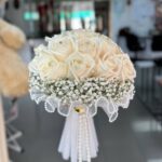 Ivory rose bridal bouquet with baby's breath, bead-style trim and hanging pearl strands
