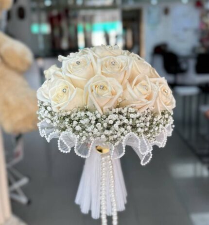 Ivory rose bridal bouquet with baby's breath, bead-style trim and hanging pearl strands