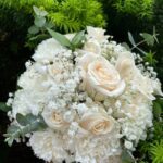White roses and ruffled white flowers with baby's breath and greenery
