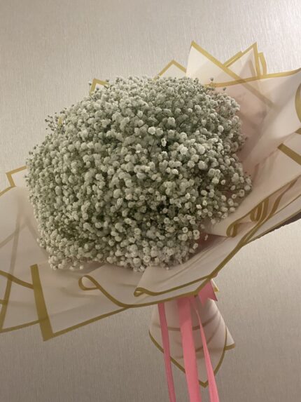 A round cloud of white baby’s breath in blush pink and gold-edged wrapping with a pink bow.