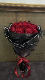 A compact cluster of red roses in sheer black and white-edged wrapping, tied with red ribbon.