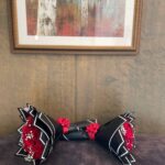 Red roses at both ends of a decorative dumbbell-shaped presentation with black wrapping.