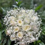 Ivory roses with white baby's breath in a rounded bridal bouquet