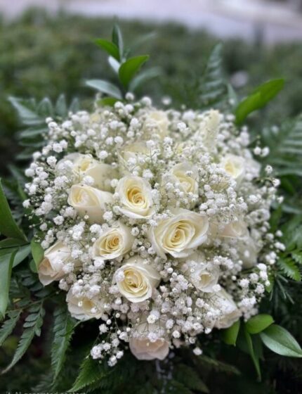 Ivory roses with white baby's breath in a rounded bridal bouquet