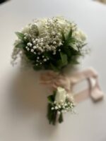 A compact ivory rose and baby’s breath bouquet with a light ribbon-wrapped handle.