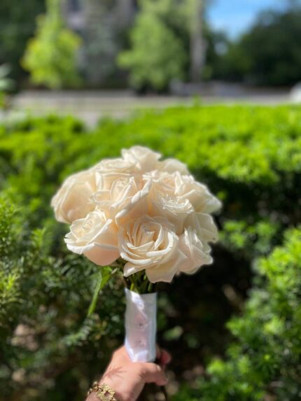 A compact ivory rose posy with a light ribbon finish for the bridal party.