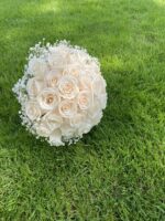 A full rounded dome of ivory roses with discreet white floral accents and a wrapped handle.