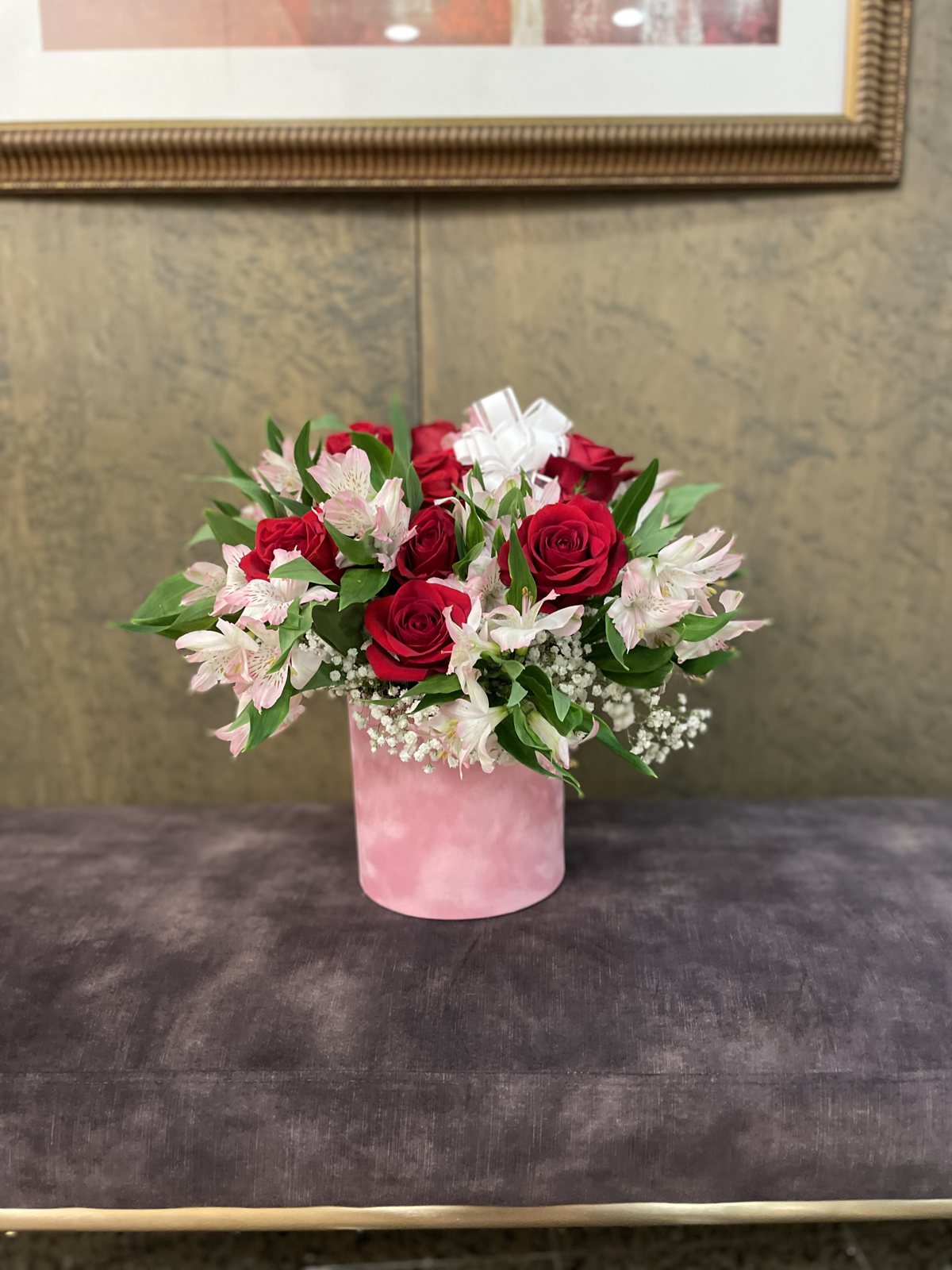 Red roses, white flowers, pink alstroemeria and baby’s breath arranged in a pink cylindrical hatbox. Red roses, white flowers, pink alstroemeria and baby’s breath arranged in a pink cylindrical hatbox.