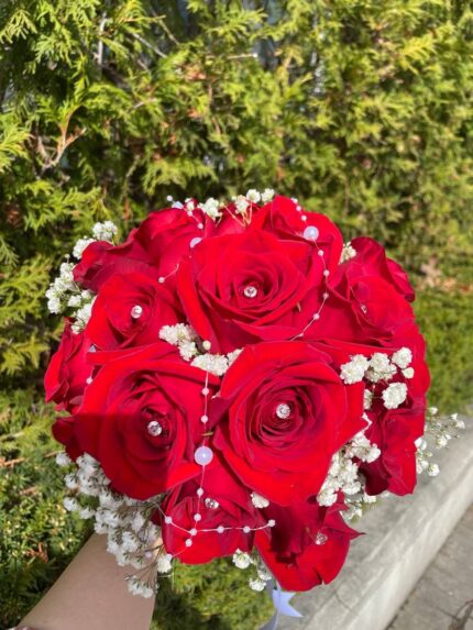A rounded red rose bridal bouquet with a white baby’s breath edge and light ribbon finish.