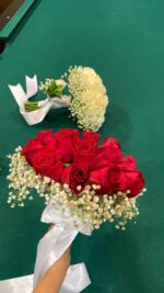 A rounded red rose bridal bouquet with a white baby’s breath edge and light ribbon finish.