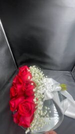 A rounded red rose bridal bouquet with a white baby’s breath edge and light ribbon finish.