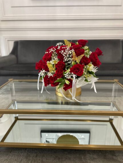 Red roses and white floral accents in a gold-tone vessel with gold butterfly decorations.