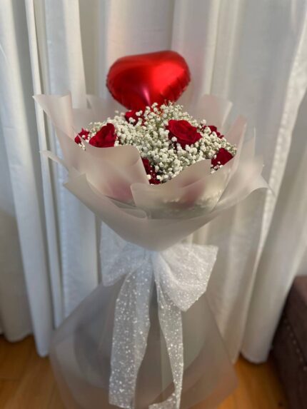 Red roses, baby’s breath and a chocolate accent in white wrapping with a red heart balloon.