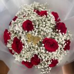 Red roses, white baby’s breath and a wrapped chocolate accent in translucent white wrapping.