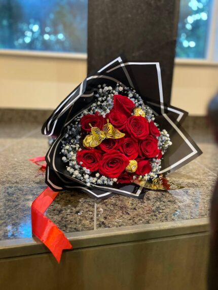 Red roses and gold-wrapped chocolates with baby’s breath and gold butterfly accents in black-and-white wrapping.