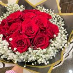 A round red rose centre framed by white baby’s breath and layered gold-edged wrapping.