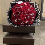 Red roses with white bead-style accents in a dramatic black-and-white geometric wrap.