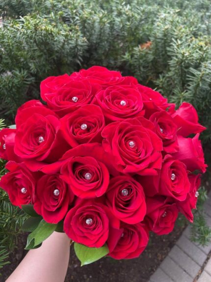 A rounded red rose bridal bouquet with small sparkling decorative accents between the blooms.