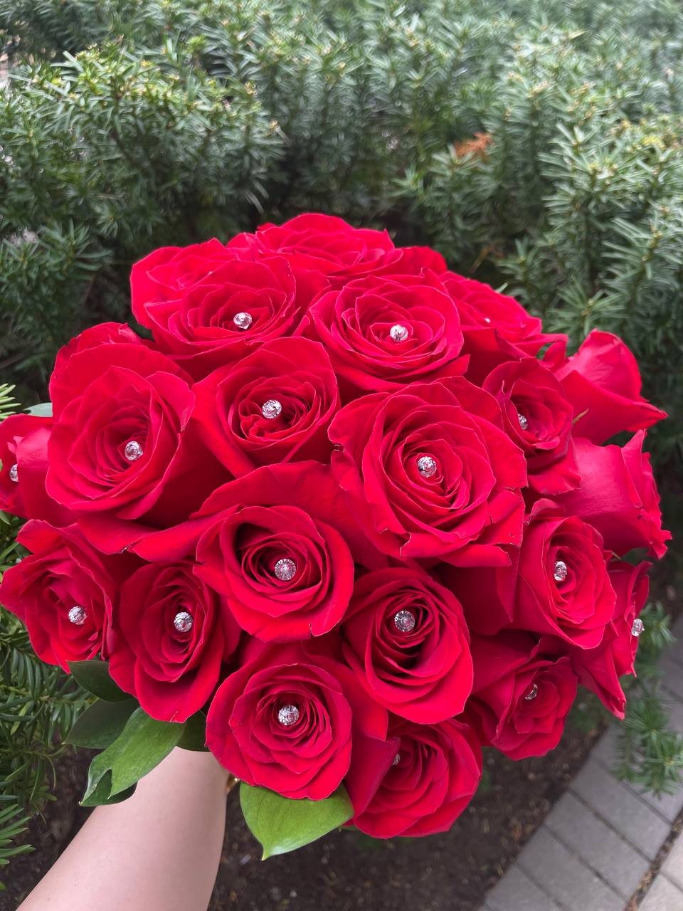 A rounded red rose bridal bouquet with small sparkling decorative accents between the blooms. A rounded red rose bridal bouquet with small sparkling decorative accents between the blooms.