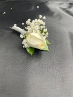A white rose with baby’s breath and green foliage on a white-wrapped stem.