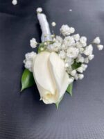 A white rose with baby’s breath and green foliage on a white-wrapped stem.