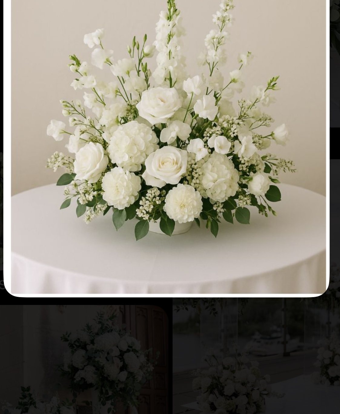 white upright ceremony arrangement A white arrangement with tall flowering stems, rounded blooms and greenery, shown in a supplied reference screenshot.
